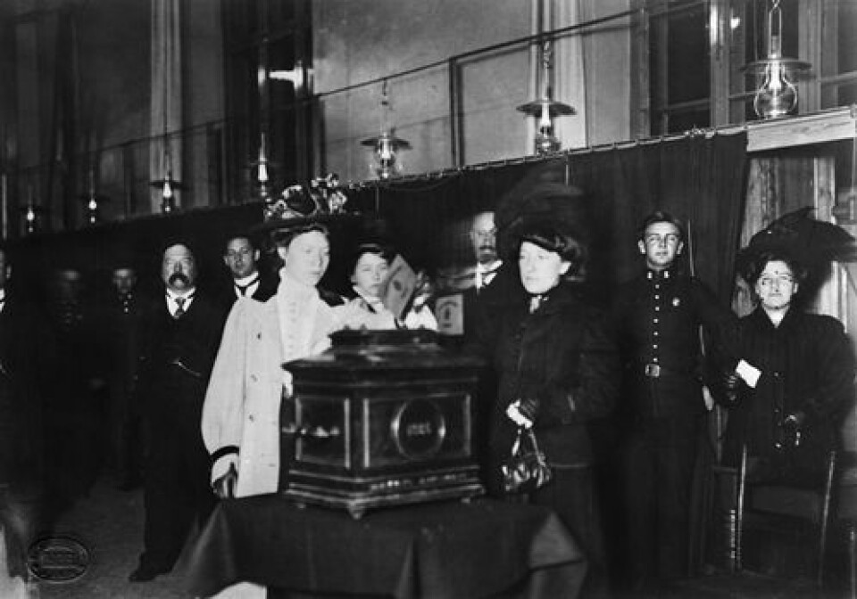 Første kvinne legger stemmeseddelen i urnen ved kommunevalget i 1910. Foto: Oslo Museum. Første kvinne legger stemmeseddelen i urnen ved kommunevalget i 1910.