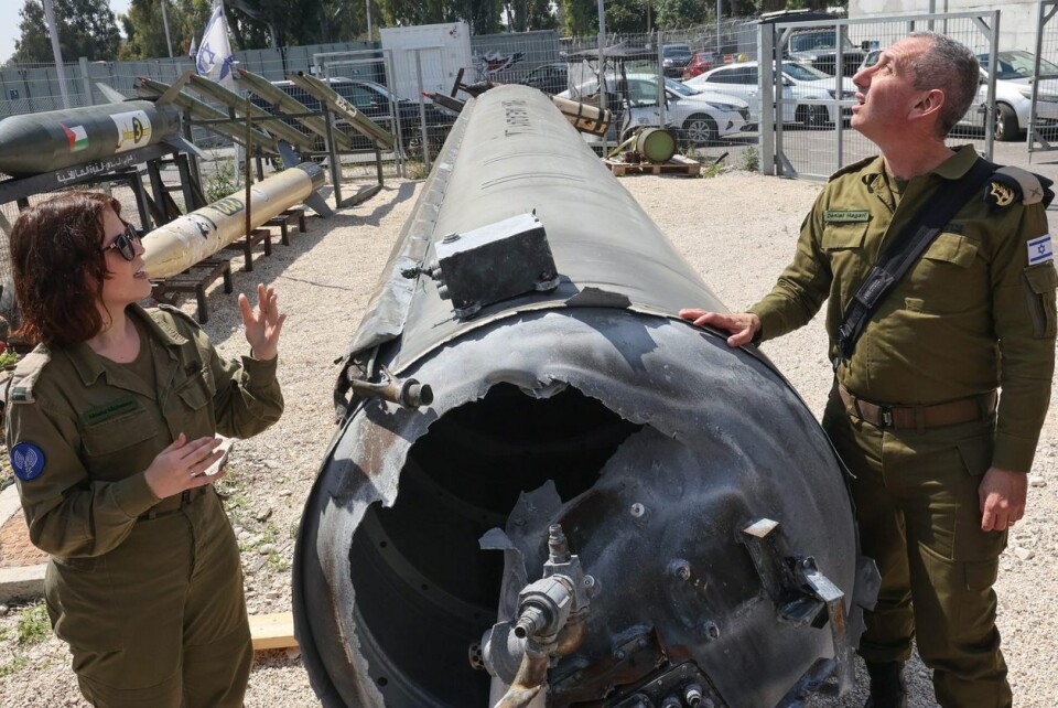 Israels militære talsperson, Daniel Hagari, og hans nestleder Masha Michelson poserer ved siden av det som skal være en iransk ballistisk missil som falt i Israel i helgen ved Julis militærbase nær den sørlige israelske byen Kiryat Malachi. Bildet er fra 16. april 2024. Foto: Gil Cohen-Magen / AFP