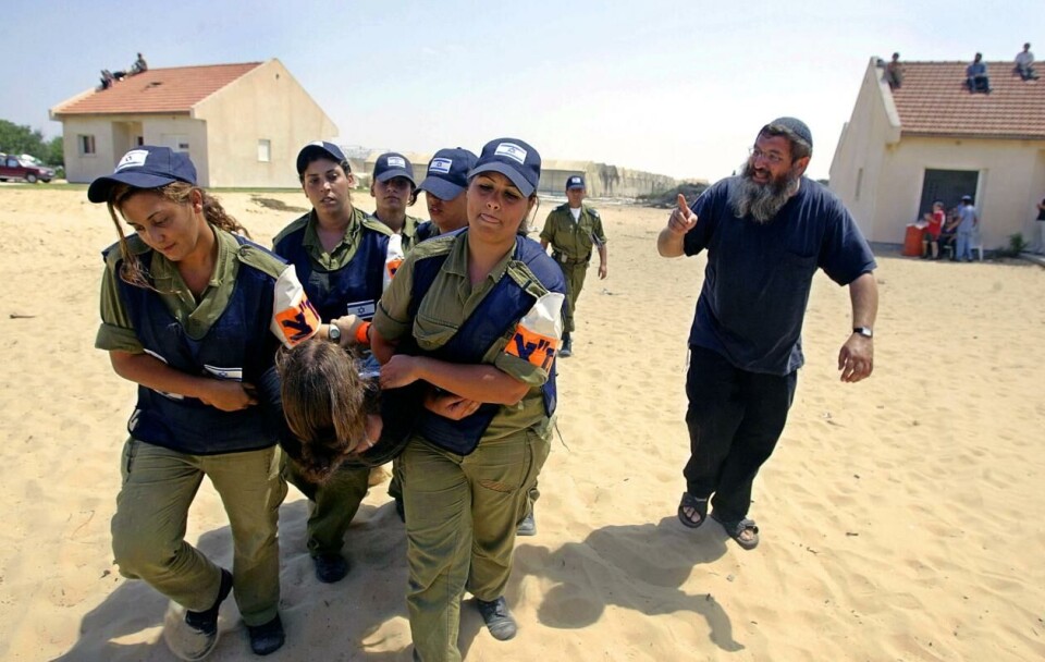 Israelsk politi bærer vekk israelske bosettere i Gadid sør i Gaza, en del av Gush Katif. Bildet er tatt under tvangsflyttingen 19. august 2005. Foto: Roberto Schmidt / AFP