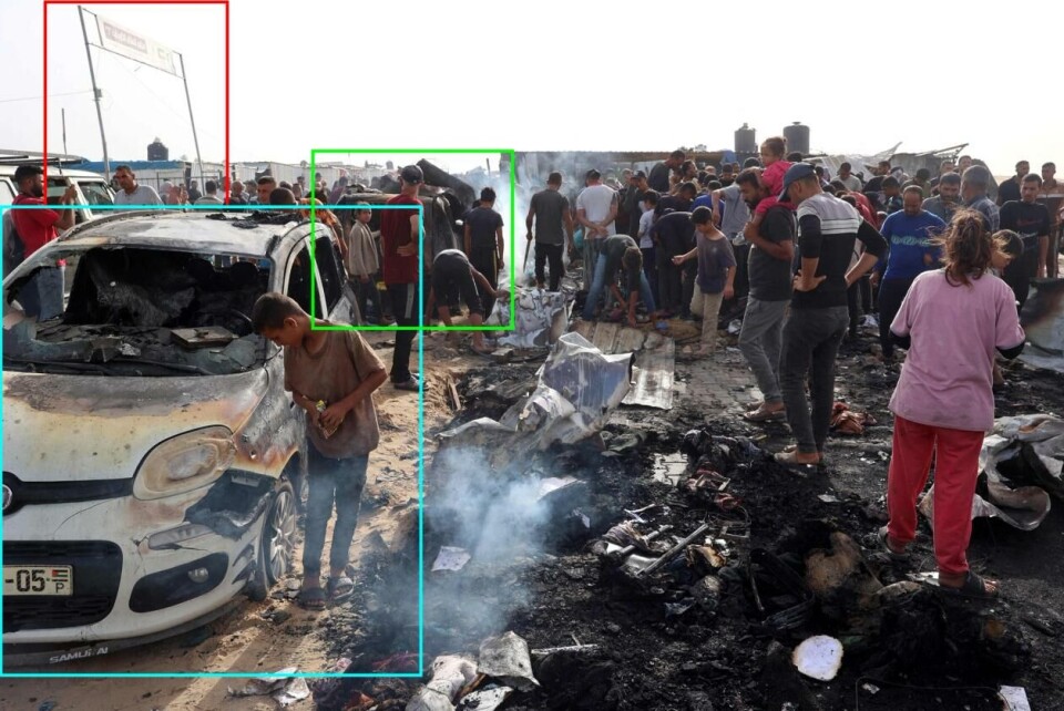 Et bilde tatt dagen etter angrepet viser to forbrente biler, og en port der det står «Kuwait Peace Camp 1». Foto: Eyad BABA /AFP, via NTB