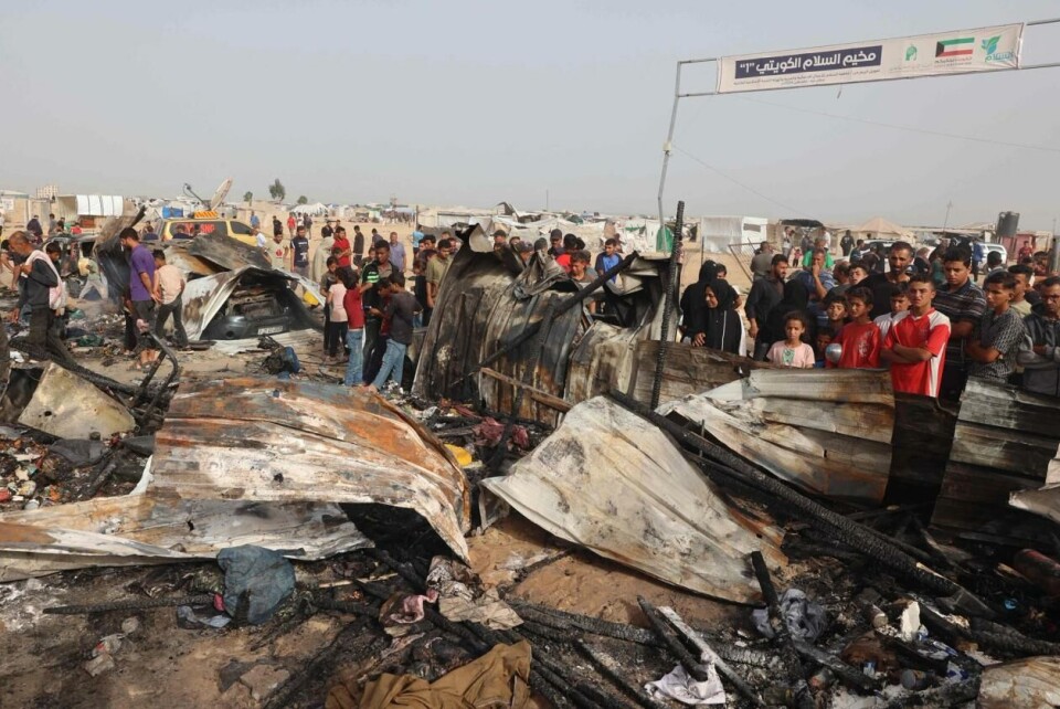 Palsinere samlet seg rundt de nedbrente skurene dagen etter angrepet. På bildet ser man porten med tekst som betyr «Kuwait Peace Camp 1», og i bakgrunnen ser vi at det er flere telt og skur i nærheten. Foto: Eyad BABA / AFP via NTB