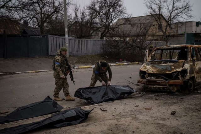 Ukrainske soldater jobber med å fjerne døde mennesker fra en utbrent bil i Butsja utenfor Kyiv i Ukraina 5. april 2022. Foto: Felipe Dana / AP Photo. hovedbilde