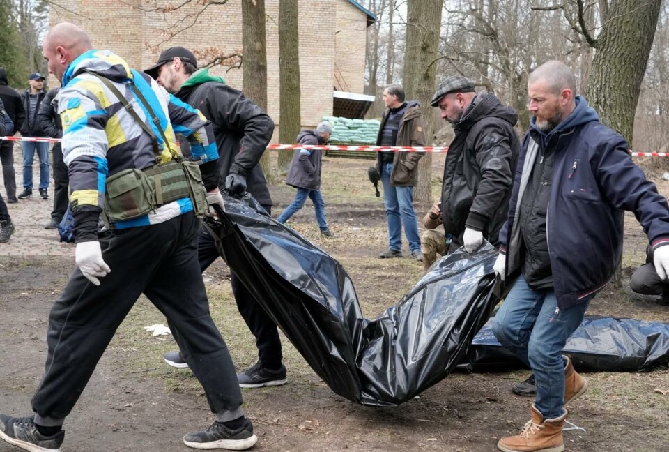 Bilder av menn som bærer bort et lik med knekk i kroppen, blir brukt av russiske myndigheter til å så tvil om hvor lenge liket har ligget. Foto: Efrem Lukatsky / AP.