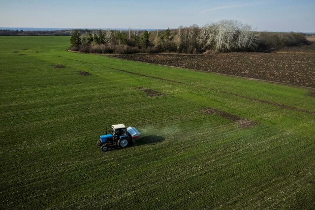 En traktor sprer gjødsel på en hveteåker nær landsbyen Yakovlivka i Ukraina, etter at flere hus i landsbyen ble truffet av bomber. Hveten for årets sesong er sådd, men ingen av de lokale bøndene vet om de vil være i stand til å høste den, skriver Reuters. Foto: Thomas Peter / Reuters. hovedbilde